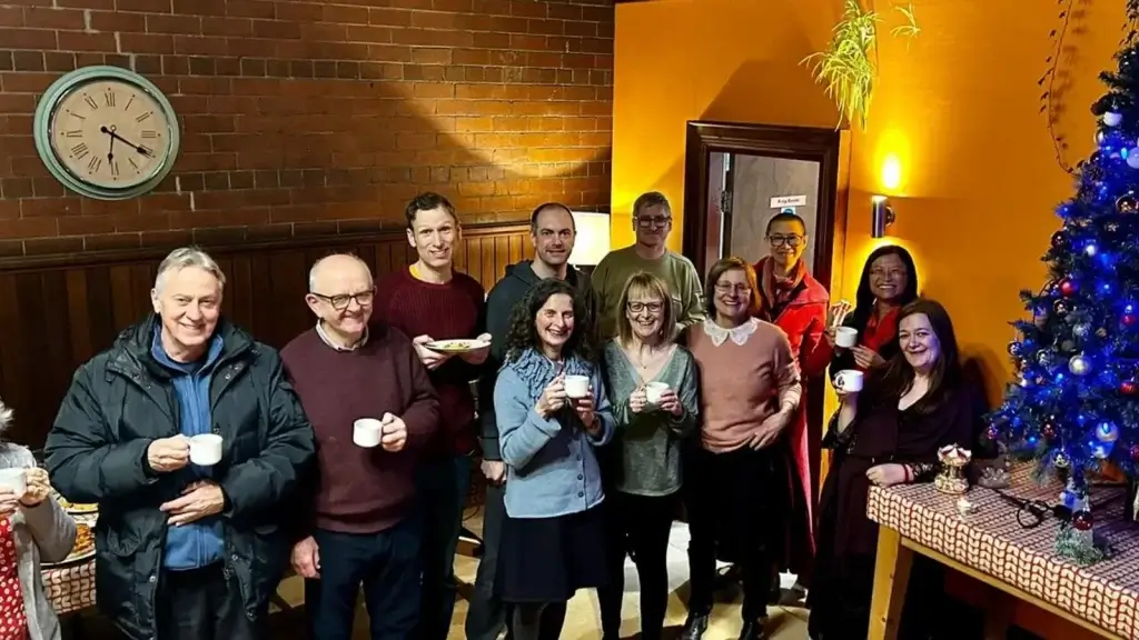 A group of people smiling at the camera who attend buddhist meditation classes at Vajrapani Kadampa Buddhist Center, Huddersfield, West Yorkshire