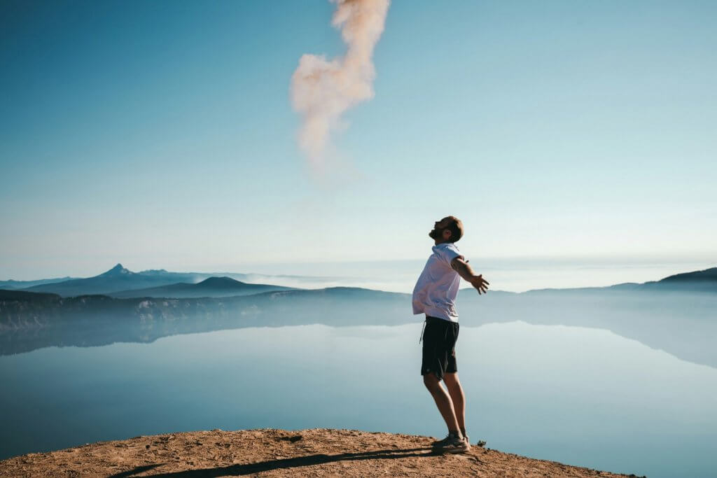 a man stretching by a lake under a clear blue sky