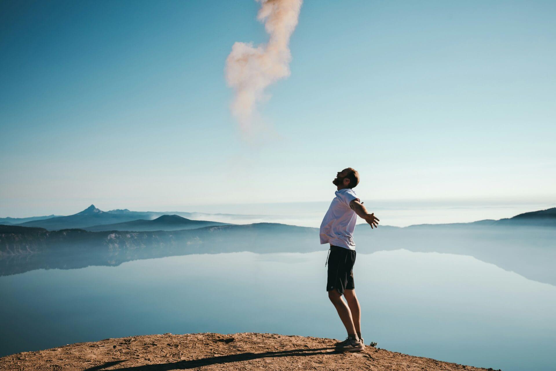 a man stretching by a lake under a clear blue sky