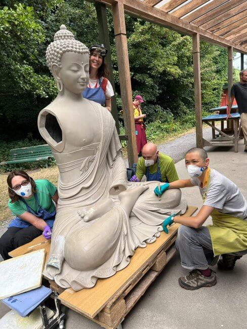 Team happily working on prepping the surface of new Buddha statue