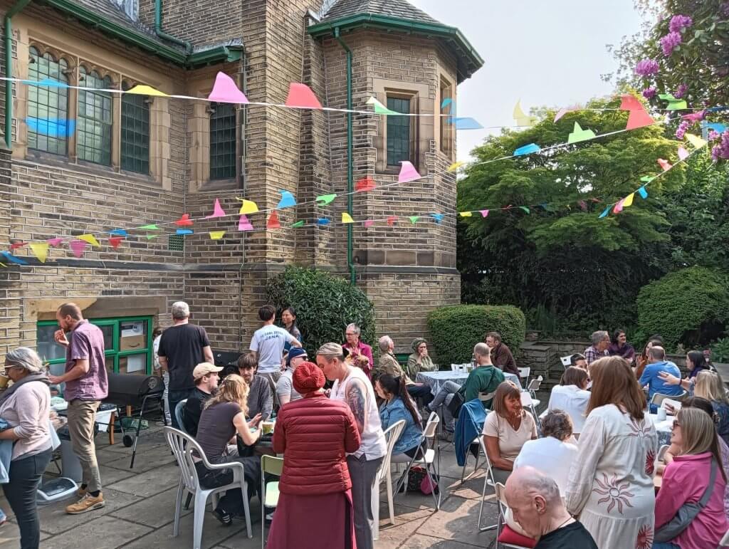 A crowd of people enjoying a BBQ event at Vajrapani Buddhist Centre