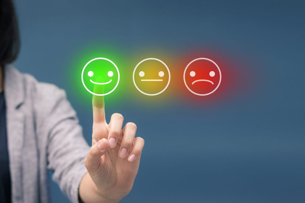 Three colorful buttons with a person choosing the button with a happy face on it.
