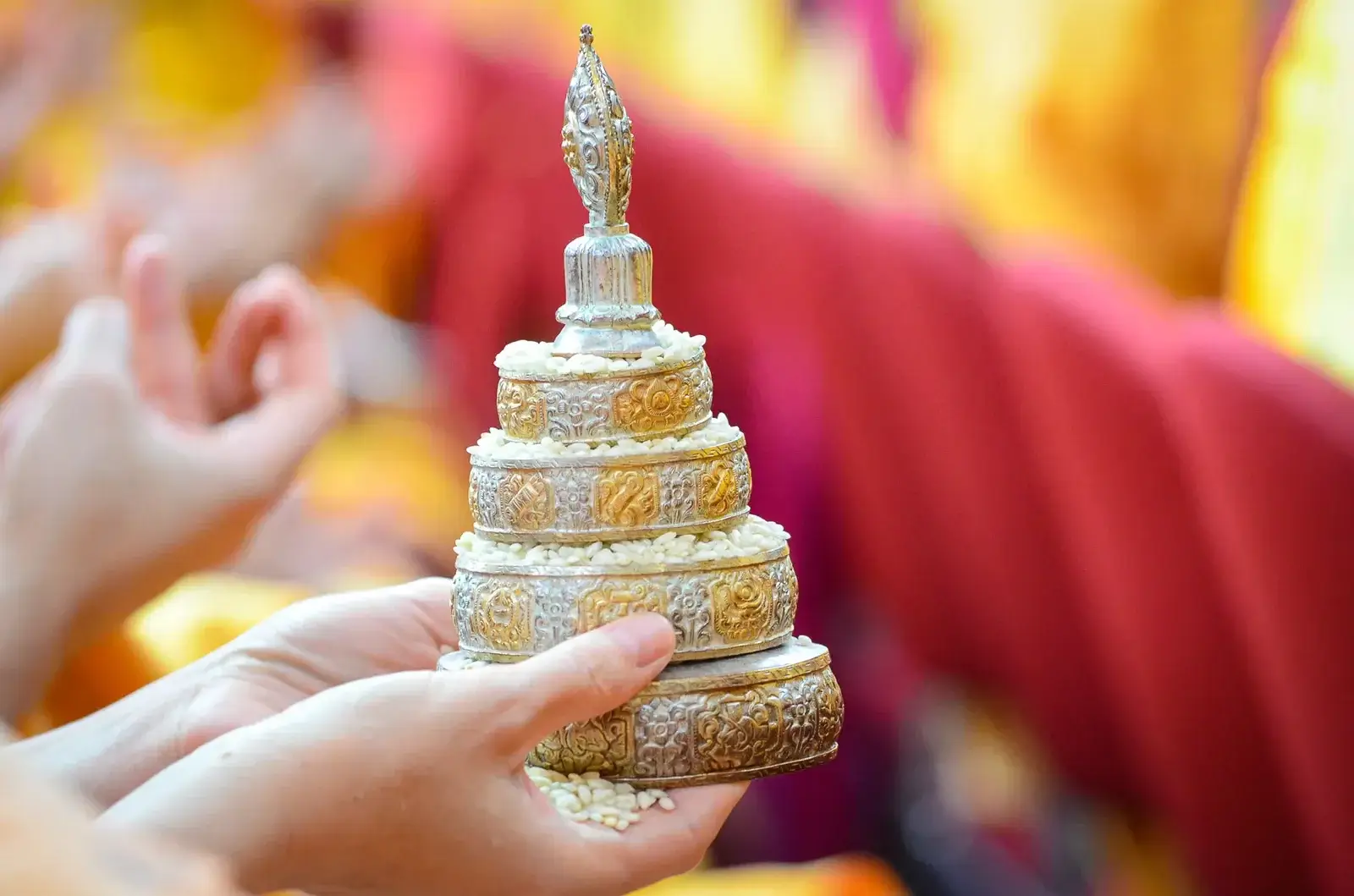 a traditional buddhist mandala offering being held in a gesture of offering