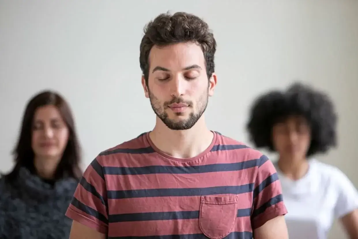 A man peacefully meditating with his eyes closed in a group
