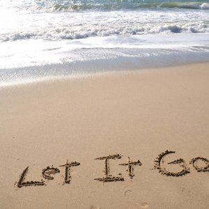 The words "Let it Go" written in sand on a beach