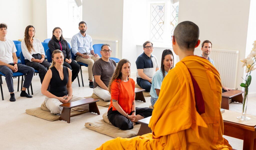 Buddhist nun Kelsang Varahi wearing traditional Buddhist robes, teaching to a mixed group of people.